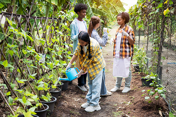 Portrait of teenage girl and boy smiling and playing in the vegetable garden.